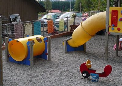 Children playing in the fenced outdoor play yard with a yellow slide