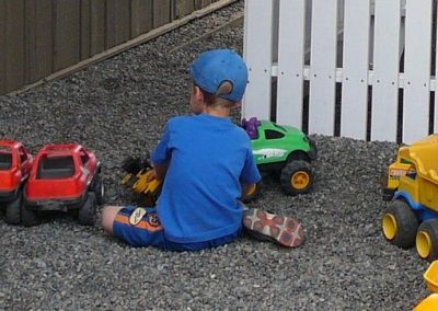 Children playing with toy trucks in the gravel